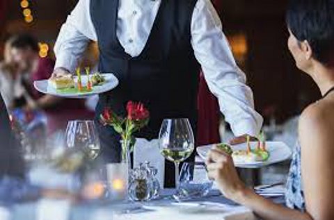 Un camarero sirve a una clienta en un restaurante.